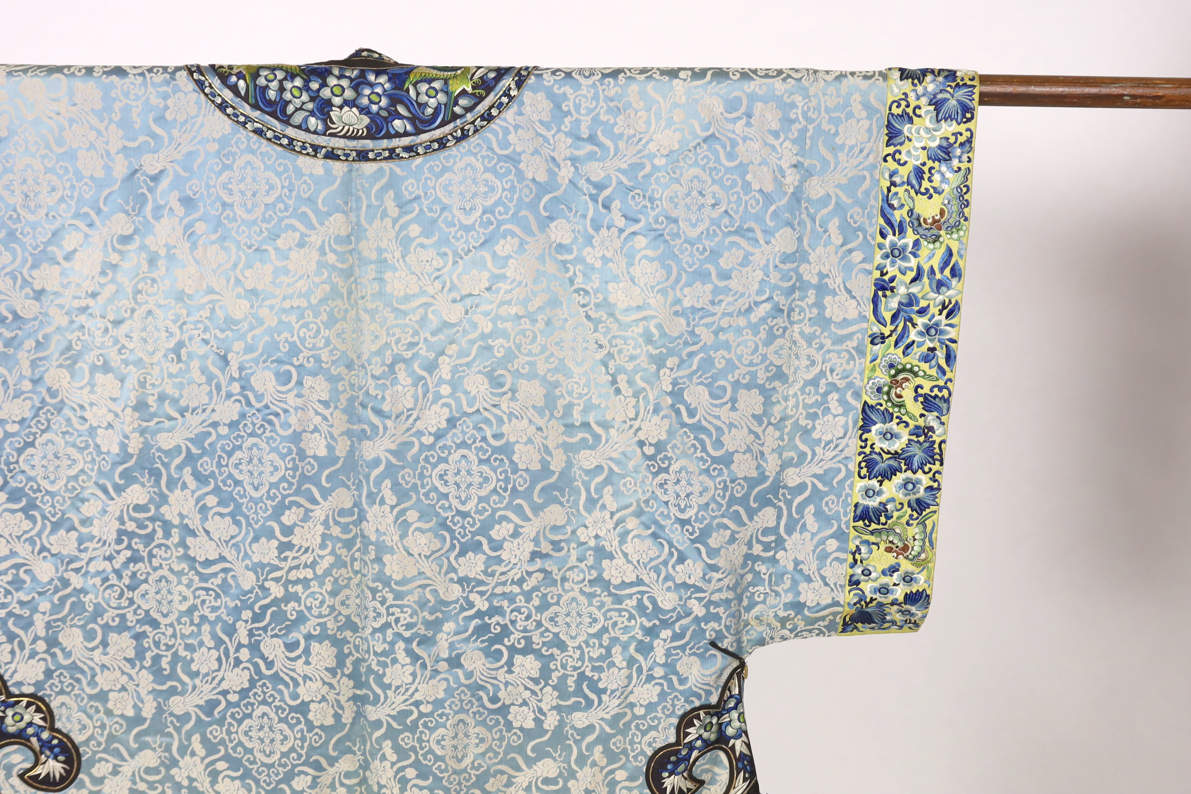 A late 19th / early 20th century silk damask robe, edged with highly ornate embroidered silk braiding, edged with fine gold and black borders, with yellow silk embroidered sleeve bands, the blue silk lining is faded in p